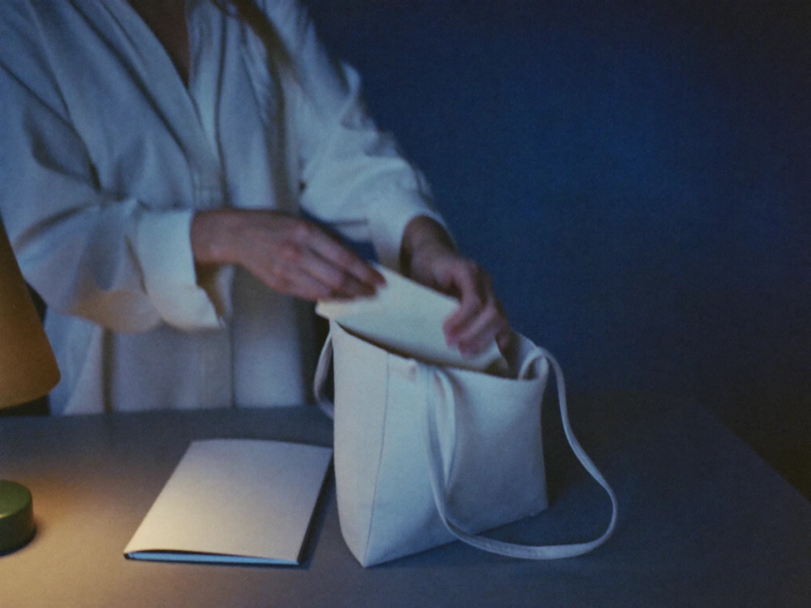 A woman packing a plain envelope into her bag before leaving home