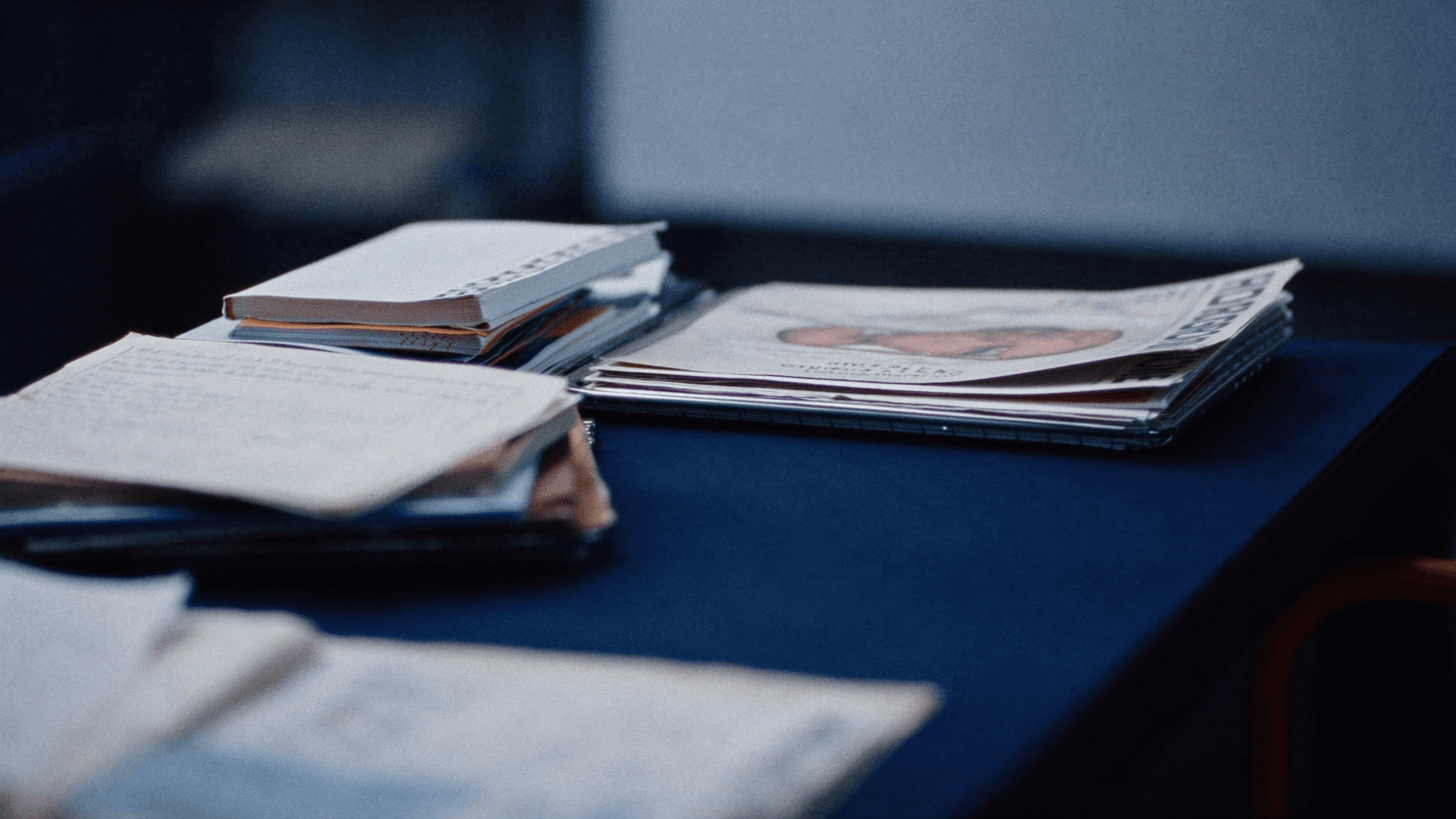 Stacked research notebooks and printed papers on a desk